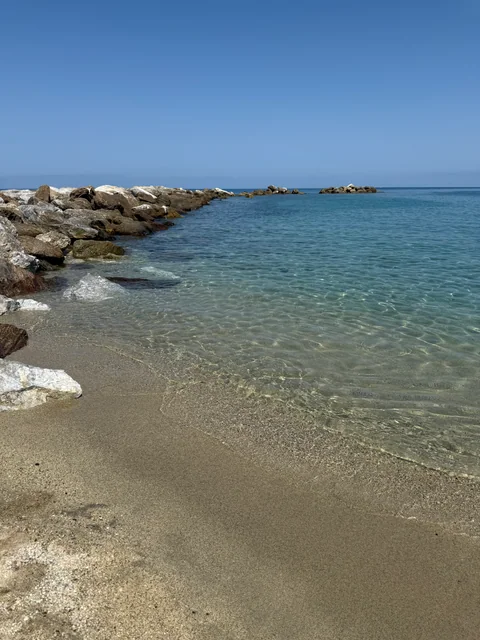 Klares Wasser und heller Sand zwischen den Felsen am freien Strand von Vibo Marina