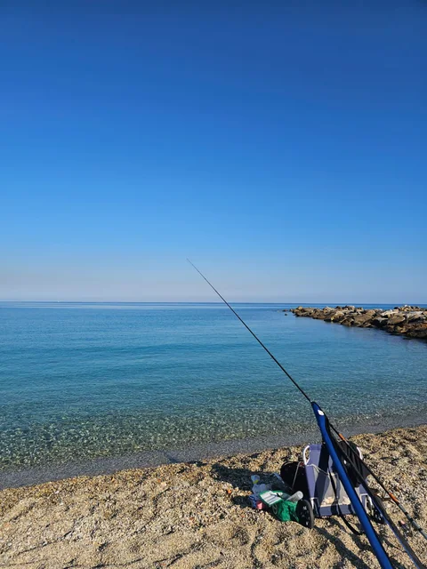 Angel und Strandstuhl am klaren Meer vor dem Wellenbrecher von Vibo Marina