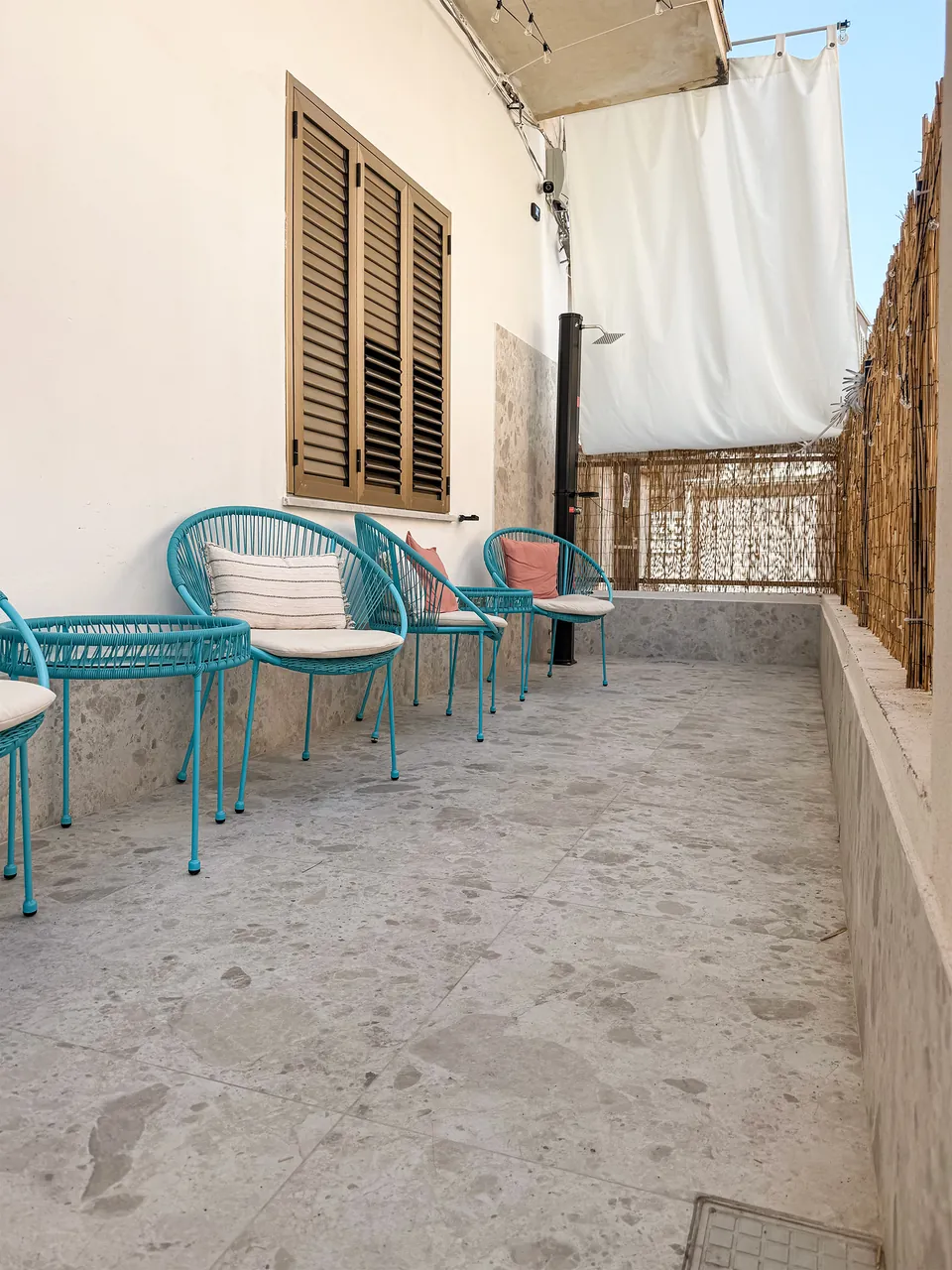Gemeinschaftsterrasse von CasaGiù mit blauen Sitzplätzen und Sonnenschutz