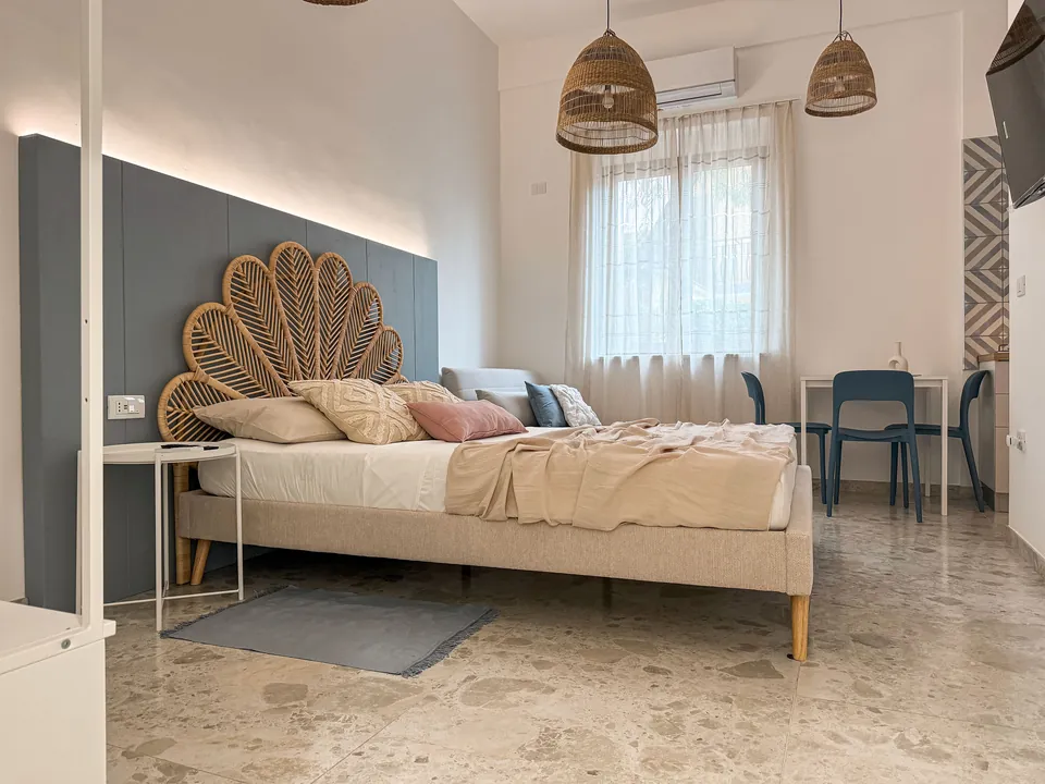 Schlafbereich im Studio Alba mit Doppelbett und Rattanleuchten